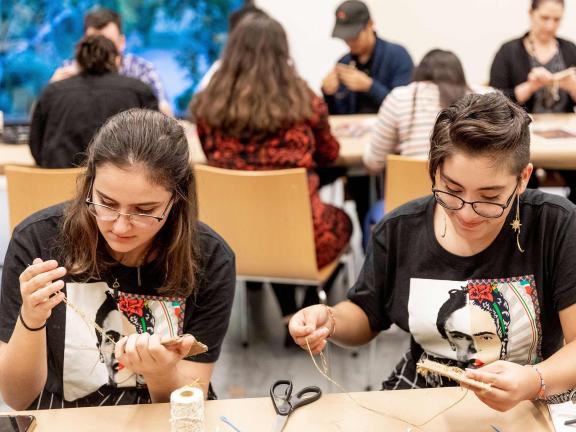 Two women sit at a table and make art.