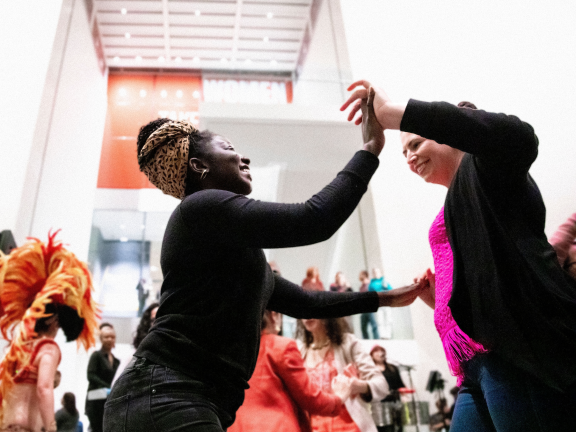 Two women hold hands and dance.